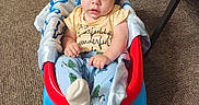 Jaxon is registered to the contest to win money with this photo: baby, blue, carpet, chair, child, clothing, colorful, face, furniture, indoors, infant, pajamas, play_equipment, portrait, red, sitting, socks, toy_seat, wide_eyed, yellow