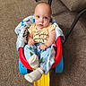 baby, blue, carpet, chair, child, clothing, colorful, face, furniture, indoors, infant, pajamas, play_equipment, portrait, red, sitting, socks, toy_seat, wide_eyed, yellow