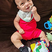 Jaxon joined the competition — help win amazing prizes! baby, bib, book, caterpillar, child, close_up, colorful, couch, happy, indoor, infant, pacifier, playtime, portrait, rattle, red_outfit, shoes, sitting, smiling, toy