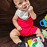 baby, bib, book, caterpillar, child, close_up, colorful, couch, happy, indoor, infant, pacifier, playtime, portrait, rattle, red_outfit, shoes, sitting, smiling, toy