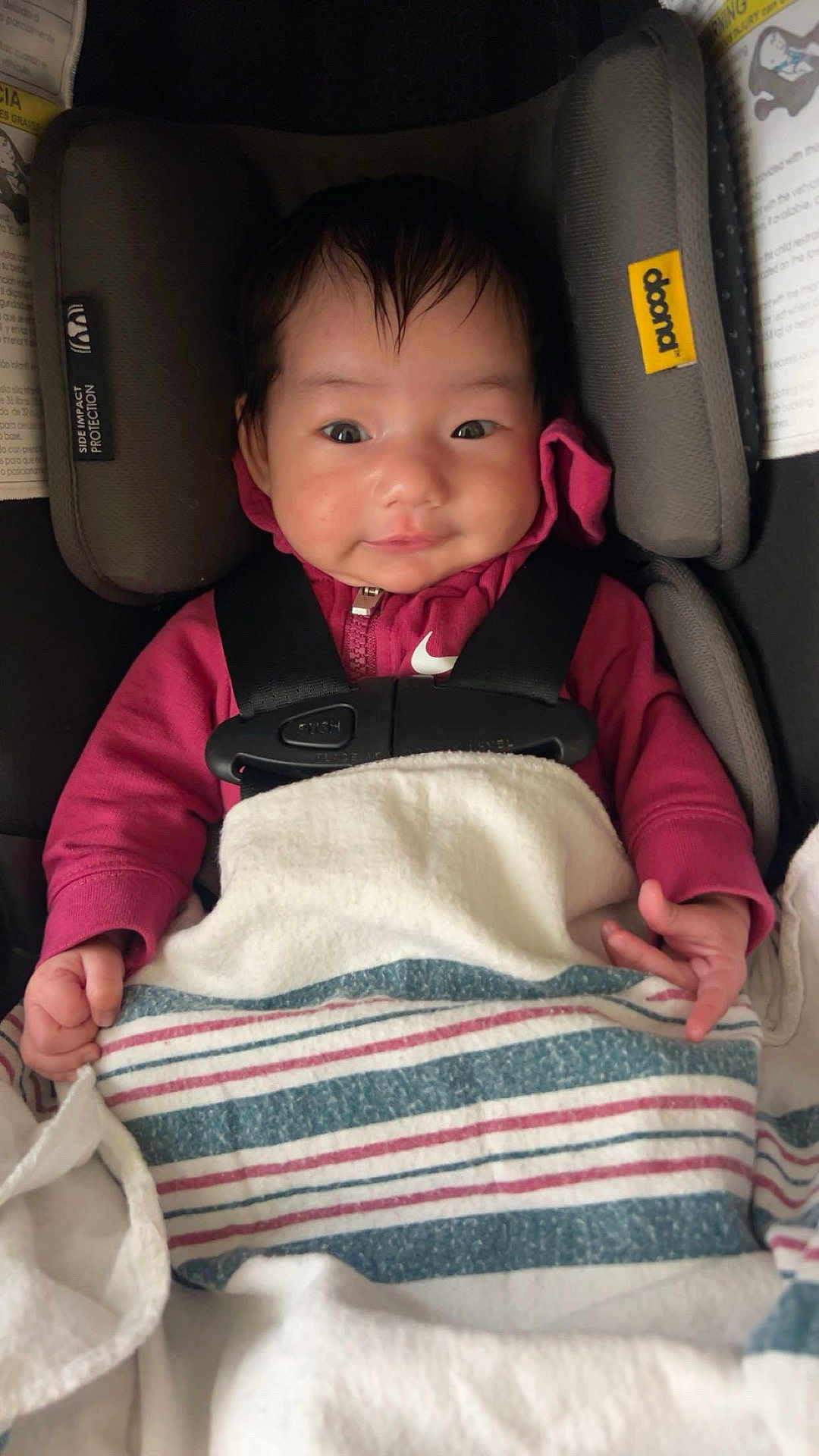Haseena joined the competition — help win amazing prizes! baby, infant, newborn, car_seat, harness, blanket, smile, hoodie, nike_logo, head_support, buckle, hands, hair, portrait, cozy, fabric, seat_padding, indoors, cute, safety