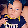 Rosalyn is registered to the contest to win money with this photo: baby, infant, blue_bow, headband, baby_clothing, onesie, freckles, blue_eyes, cute, indoor, portrait, child, person, hand, face, smiling, close_up, daisy, yellow, navy_blue