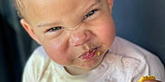 Ilani joined the competition — help win amazing prizes! toddler, child, face, expression, food, cake, crumbs, hand, white_shirt, messy, portrait, indoor, cheek, skin, eyes, curly_hair, cute, snack, emotion, person