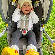 Ilani joined the competition — help win amazing prizes! baby, child, stroller, hat, yellow_shoes, smiling, happy, outdoor, grass, baby_clothing, car_seat, infant, cute, playful, person, legs, feet, headwear, sitting, baby_accessory