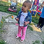 toddler, denim_jacket, pink_pants, sandals, grass, concrete, lawnmower, playground, children, outdoor, fence, toy, daylight, curly_hair, casual_clothing, sidewalk, play_equipment, people, summer, backyard