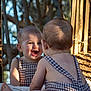 baby, bare_back, checkered_clothing, child, cute, daylight, happy, infant, mirror, nature, outdoor, playful, portrait, reflection, sitting, skin, smile, sunlight, trees, young_child