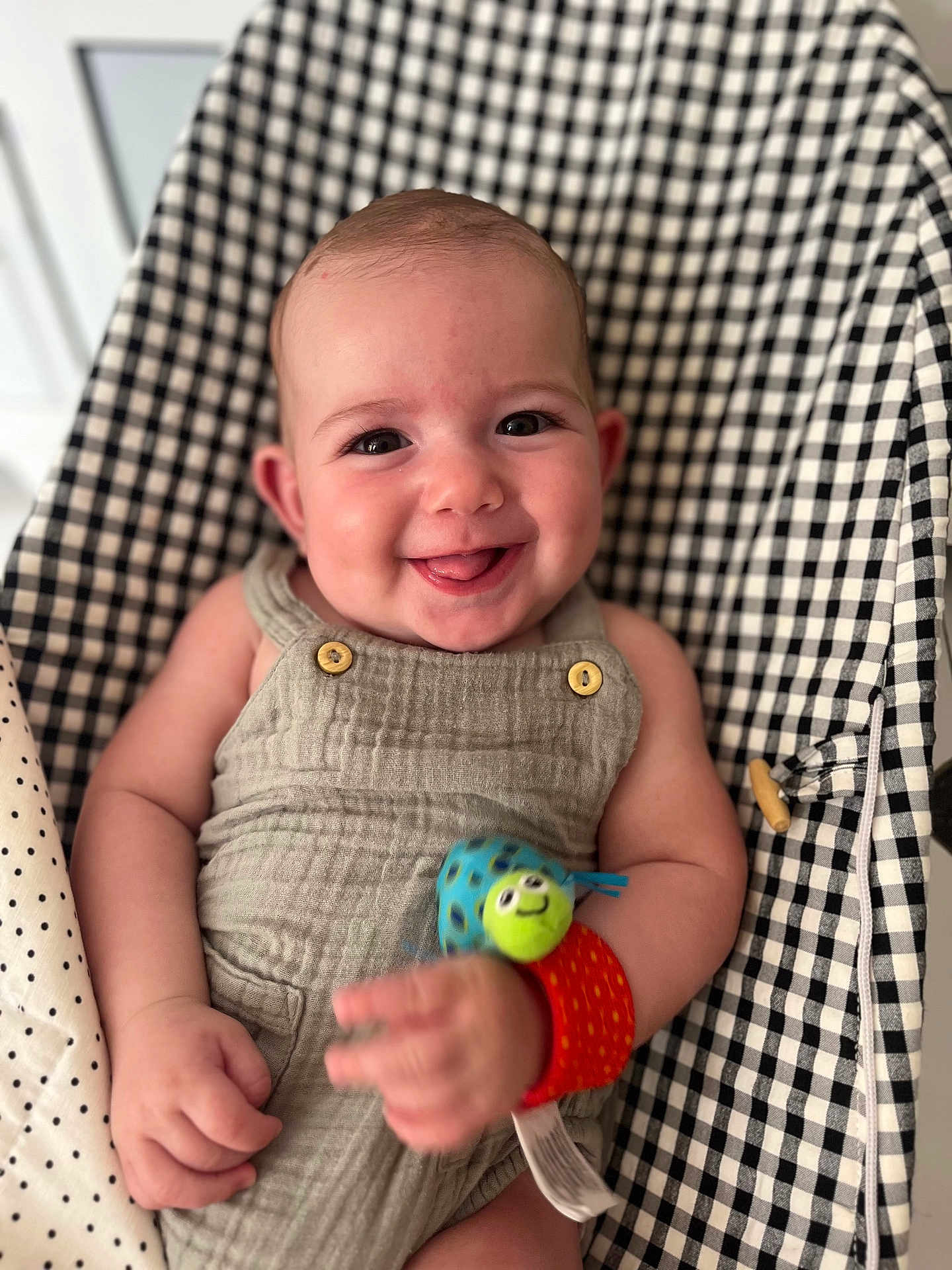 Camille a rejoint le concours — aidez-le/la à gagner de superbes lots ! baby, smiling, child, wrist_toy, romper, cushion, checkered_pattern, happy, indoor, infant, person, cute, seated, close_up, skin, playful, bright, eyes, hand, soft_fabric