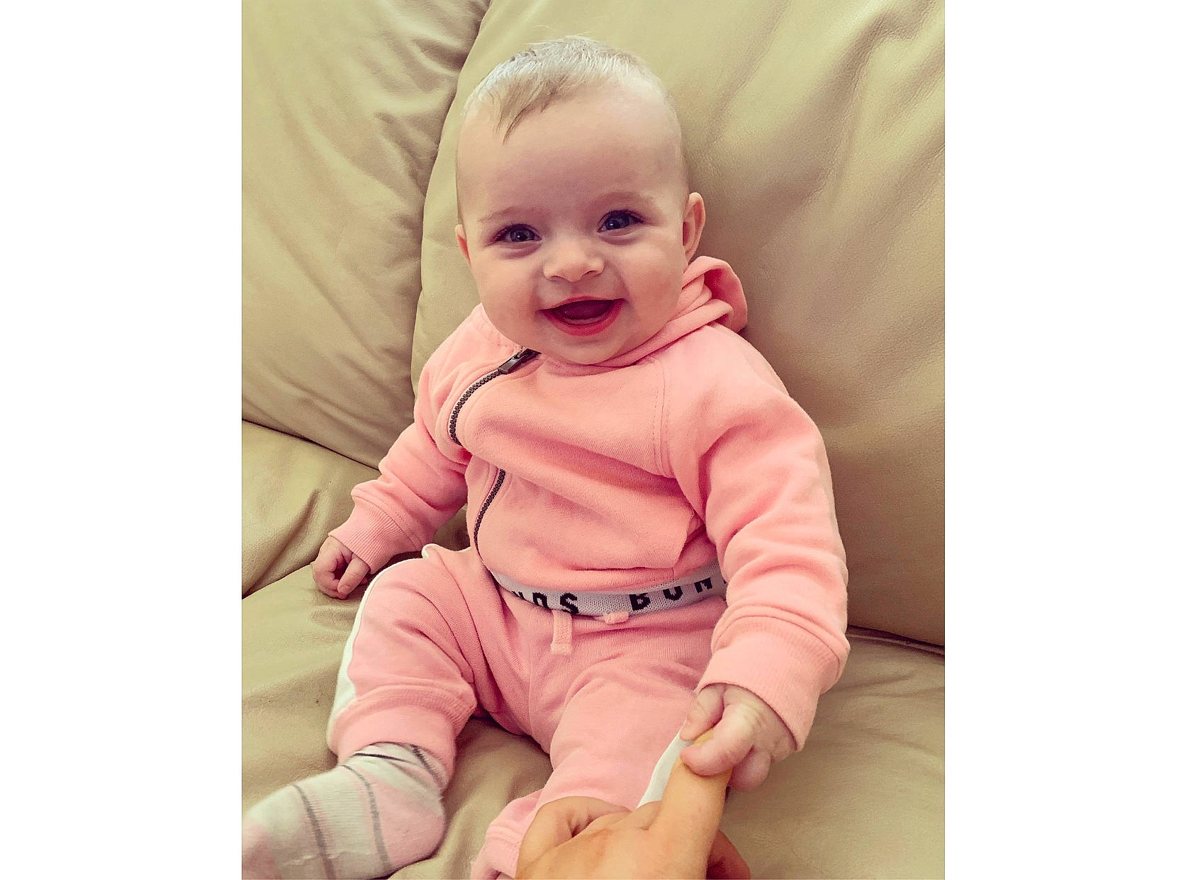 Edith is registered to the contest to win money with this photo: arm, baby, baby_laughing, baby_products, baby_toddler_clothing, beige, cheek, child, child_model, dress, head, outerwear, person, pink, product, sitting, skin, sleeve, smile, t_shirt