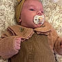 baby, pacifier, headband, bow, corduroy, sweater, blanket, floral_pattern, infant, closeup, sleepy, cute, child, portrait, soft_texture, hand, face, lying_down, warm_clothing, indoors