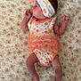 Sienna is registered to the contest to win money with this photo: baby, infant, floral_pattern, headband, bow, onesie, ruffles, blanket, laying_down, side_view, cute, newborn, clothing, small_hands, small_feet, skin, person, indoors, soft, colorful