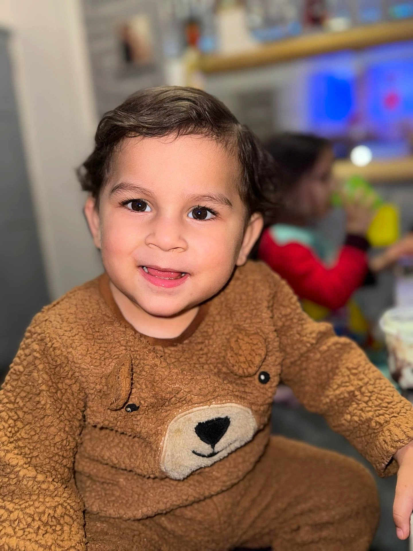 Elijah joined the competition — help win amazing prizes! child, toddler, smiling, brown_outfit, bear_theme, fuzzy_clothing, indoor, portrait, face, happy, cute, young_child, playful, person, sitting, cozy, background_blur, drinking, multicolor_clothing, eyes