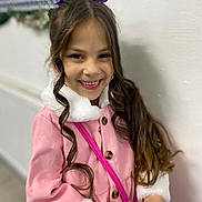 Selina is registered to the contest to win money with this photo: child, girl, smiling, pink_coat, curly_hair, purple_bow, bracelet, portrait, indoor, happy, fashion, person, cute, young, clothing, accessory, long_hair, button, white_fur, holding