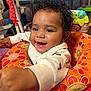 baby, child, smiling, curly_hair, baby_seat, colorful, indoor, toy, happy, face, clothing, person, playful, infant, closeup, bright, cute, portrait, young_child, warm