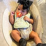 Fayth is registered to the contest to win money with this photo: baby, infant, pacifier, black_bow, bib, cushion, seat, clothing, shoes, indoor, child, face, headband, legs, cute, comfort, relaxing, soft_texture, patterned_fabric, small_person