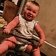 Blakeley joined the competition — help win amazing prizes! baby, child, smiling, indoor, carpet, game_controller, toy, person, couch, door, wall, clothing, foot, hand, furniture, living_room, playing, happy, sitting, cute