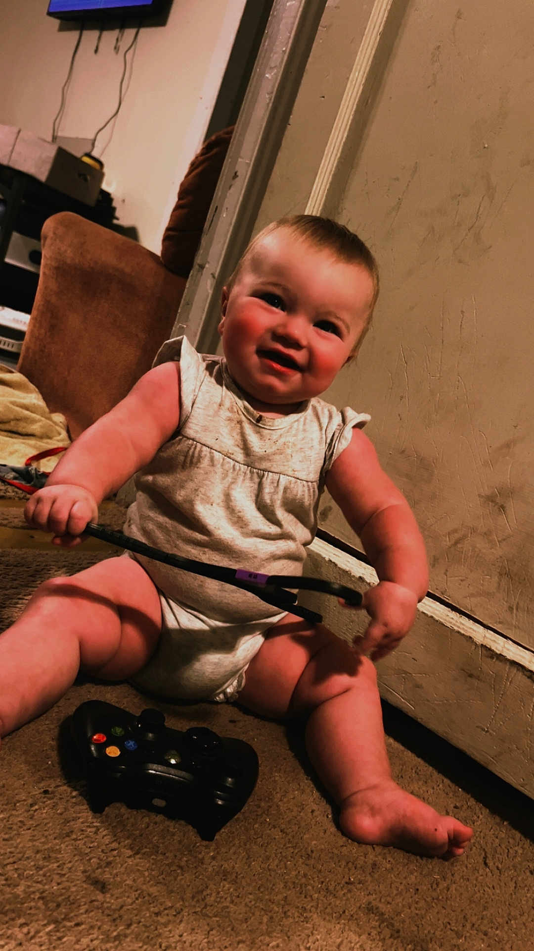 Blakeley joined the competition — help win amazing prizes! baby, child, smiling, indoor, carpet, game_controller, toy, person, couch, door, wall, clothing, foot, hand, furniture, living_room, playing, happy, sitting, cute