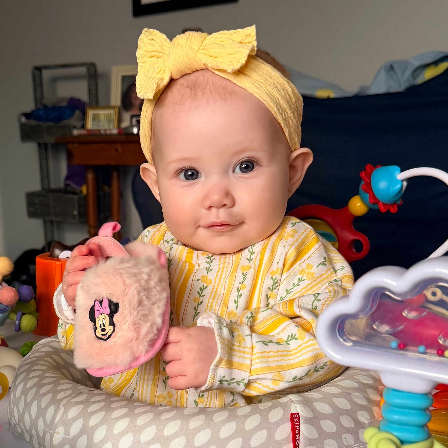 Genevieve is registered to the contest to win money with this photo: baby, blue_eyes, bow, child, cute, face, hands, headband, indoor, infant, minnie_mouse, photography, play_seat, plush_toy, portrait, seat_cushion, smile, striped_clothing, toy, yellow_clothing