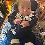 Alexander joined the competition — help win amazing prizes! baby, infant, clothing, socks, person, face, hands, sitting, indoor, blanket, furniture, laundry_basket, floor, wooden_floor, adult, home, cozy, smile, cute, portrait