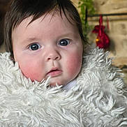 Raphaëlle a rejoint le concours — aidez-le/la à gagner de superbes lots ! baby, child, face, blanket, fluffy, indoor, portrait, curious, rosy_cheeks, dark_hair, cozy, warm, candid, closeup, person, soft_texture, expression, young, wrapped, infant
