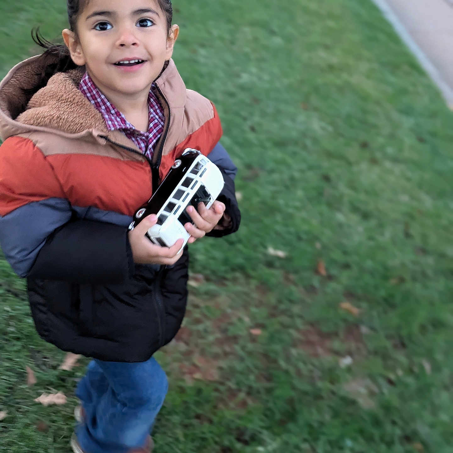 Leiam is registered to the contest to win money with this photo: bodypart, child, clothing, coat, face, female, finger, footwear, girl, grass, hand, head, jacket, lawn, pants, person, photography, plant, portrait, shoe