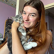 Mimi joined the competition — help win amazing prizes! woman, cat, kitten, indoor, portrait, smile, long_hair, red_hair, animal, pet, love, affection, holding, young_adult, casual_clothing, purple_wall, wallpaper, door, natural_light, cozy