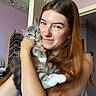 woman, cat, kitten, indoor, portrait, smile, long_hair, red_hair, animal, pet, love, affection, holding, young_adult, casual_clothing, purple_wall, wallpaper, door, natural_light, cozy