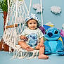 Justin is registered to the contest to win money with this photo: toddler, child, swing, macrame, hat, blue_background, plush_toy, stitch_character, toy, plant, cloud_prop, indoor, smiling, cute, sitting, clothing, barefoot, portrait, decor, playful