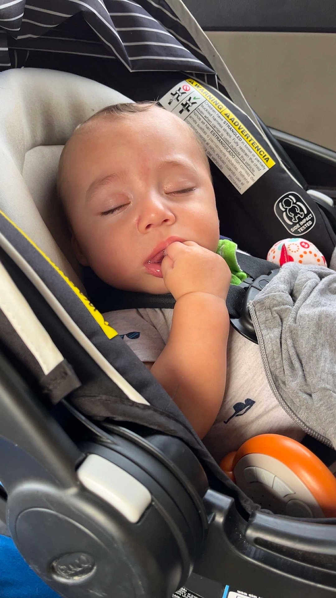 Jermaine is registered to the contest to win money with this photo: baby, car_seat, sleeping, child, infant, hand, blanket, toy, clothing, seatbelt, face, closeup, peaceful, resting, indoors, comfort, young_child, cute, napping, portrait