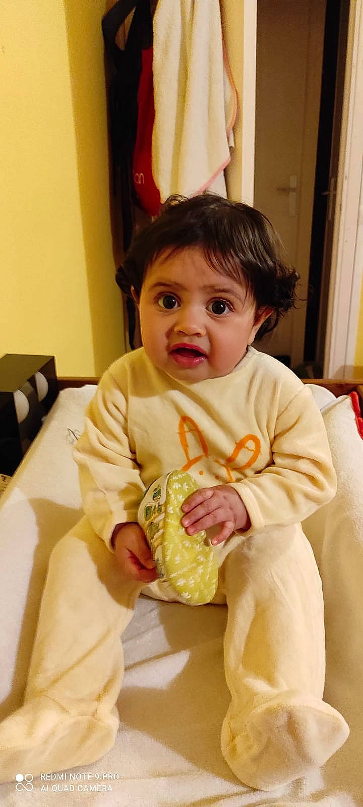 Jana a rejoint le concours — aidez-le/la à gagner de superbes lots ! baby, baby_toddler_clothing, bib, chair, cheek, child, comfort, curtain, face, fun, happy, nose, peach, person, room, sitting, skin, sleeve, surprise, t_shirt