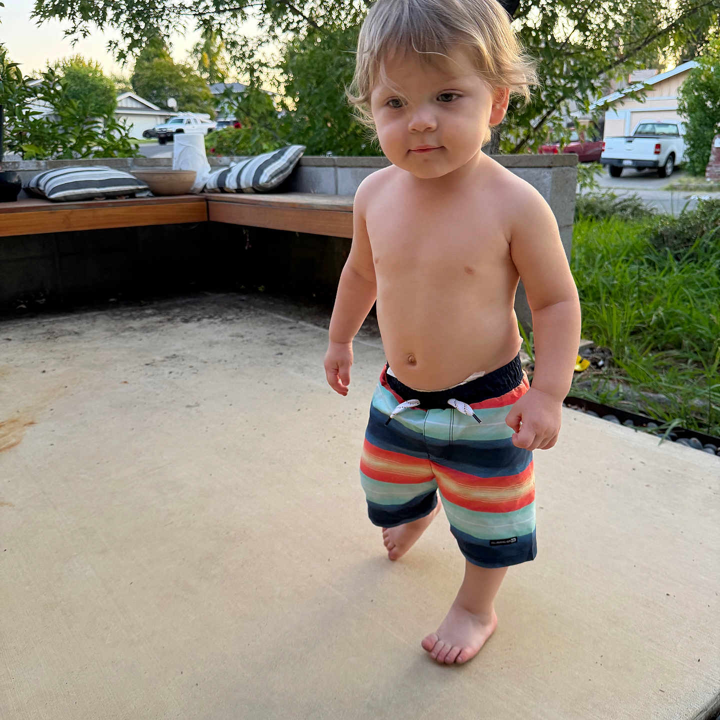 Aj is registered to the contest to win money with this photo: toddler, child, barefoot, shorts, outdoor, patio, concrete, trees, greenery, bench, cushions, house, car, daylight, summer, person, cute, young, walking, casual