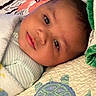 baby, blanket, quilt, turtle, face, infant, child, lying_down, soft_texture, striped_clothing, bed, comfort, cute, portrait, sleepwear, head, peaceful, indoors, closeup, resting