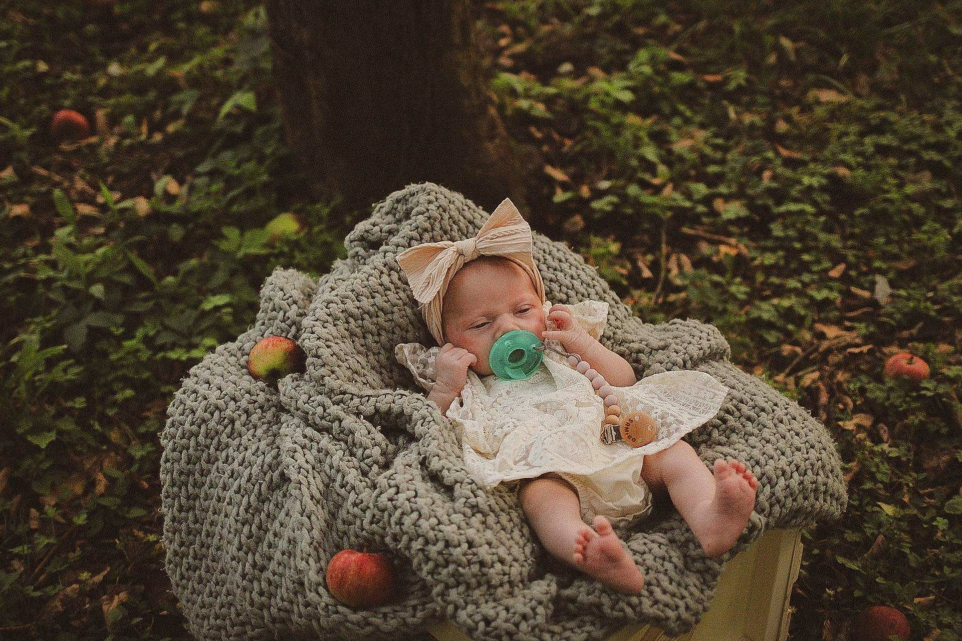 Blair is registered to the contest to win money with this photo: baby, baby_toddler_clothing, cap, child, forest, garden, grass, grass_family, hand, happy, knit_cap, people_in_nature, person, plant, rock, sitting, sun_hat, toddler, tree, wood
