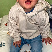 Lenny participe au concours pour gagner de l'argent avec cette photo : baby, child, smiling, hoodie, jeans, sitting, cushion, paw_print, indoor, happy, cute, portrait, clothing, feet, sock, face, person, infant, casual, green_background