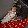 baby, sleeping, pacifier, blanket, couch, pillow, polka_dot, swaddled, indoor, comfort, rest, infant, peaceful, soft, cozy, child, person, homedecor, relaxation, nap