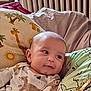 animal_print, baby, child, closeup, comfort, cozy, cushion, cute, furniture, giraffe_pattern, green_shirt, home, indoor, infant, necklaces, person, portrait, relaxed, smiling, soft_lighting