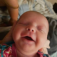 Addison is registered to the contest to win money with this photo: baby, smiling, close_up, sleeping, infant, face, child, person, colorful_clothing, floral_pattern, bed, blanket, hand, skin, head, peaceful, indoors, portrait, newborn, happy