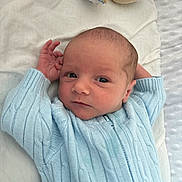 Archie is registered to the contest to win money with this photo: baby, infant, blue_clothing, knitwear, blanket, plush_toy, soft_texture, cute, newborn, portrait, hand, face, eyes, lying_down, resting, indoors, cozy, sleepwear, child, young