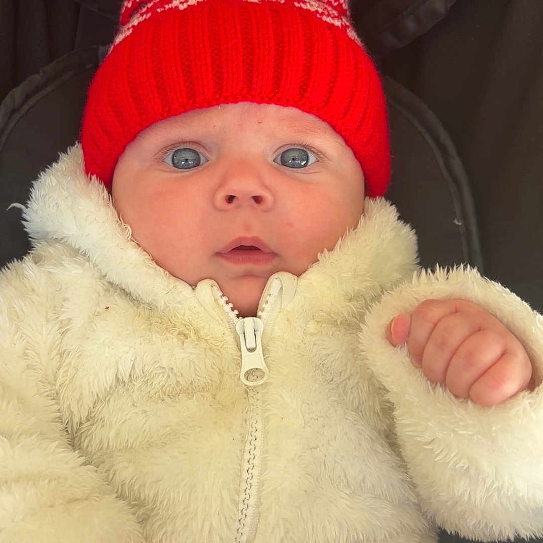 Cylian participe au concours pour gagner de l'argent avec cette photo : baby, child, closeup, curious, cute, face, fluffy_clothing, hands, headwear, infant, outdoor_gear, pom_pom, portrait, red_hat, soft_texture, stroller, warm, white_jacket, wide_eyes, winter_clothing