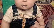 Wyatt is registered to the contest to win money with this photo: baby, infant, child, sitting, portrait, wide_eyes, looking_at_camera, playroom, indoor, colorful_carpet, playground, slide, soft_play, overalls, beige_shirt, barefoot, pacifier, patterned_rug, centered_composition, candid_photo