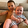 baby, child, sibling, couch, striped_clothing, smile, happy, indoor, portrait, bare_chest, furniture, living_room, person, cute, young_child, infant, family, relaxing, skin, foot