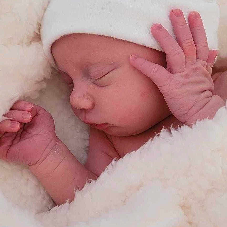 Liam joined the competition — help win amazing prizes! baby, bed, blanket, bodypart, bonnet, cap, clothing, face, finger, furniture, hand, happy, hat, head, newborn, person, photography, portrait, sleeping, smile