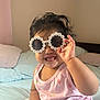 toddler, child, sunglasses, flower_glasses, smile, happy, indoor, bed, bedding, pink_tank_top, cute, portrait, hair, hand, furniture, person, skin, light, casual_wear, playful