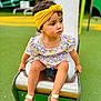 toddler, child, playground, slide, yellow_headband, floral_dress, sandals, outdoor, green, play_equipment, summer, cute, sitting, curious, young_child, park, feet, person, daytime, playtime