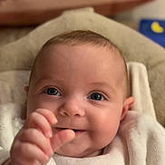 Simone a rejoint le concours — aidez-le/la à gagner de superbes lots ! baby, close_up, smiling, blanket, infant, hand, face, blue_eyes, soft_texture, cute, cozy, indoors, portrait, child, happy, young, skin, expression, warm, comfort