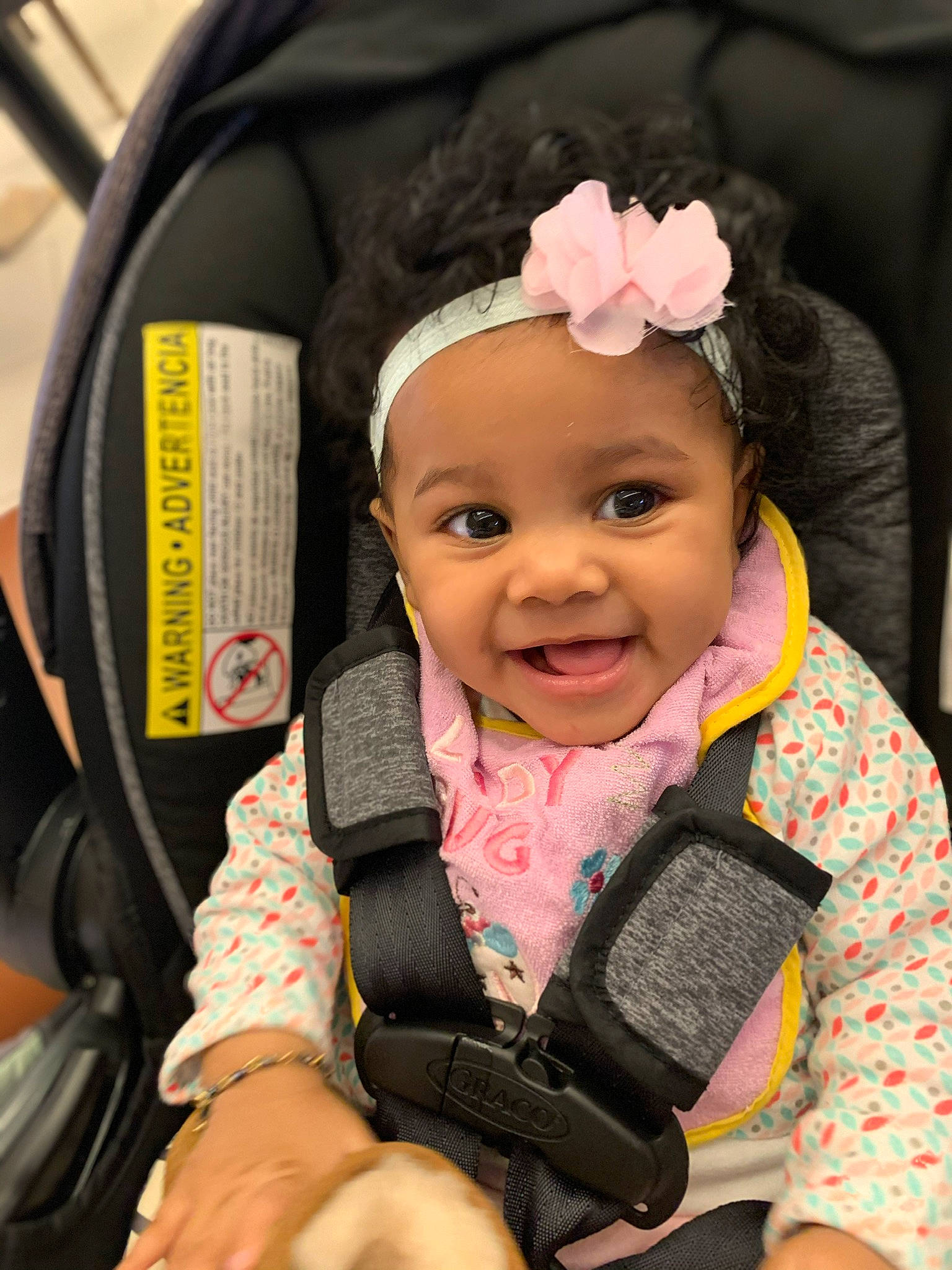 Riley is registered to the contest to win money with this photo: auto_part, baby, baby_carriage, baby_in_car_seat, baby_products, car_seat, cheek, child, headband, headwear, joy, person, pink, product, smile, toddler