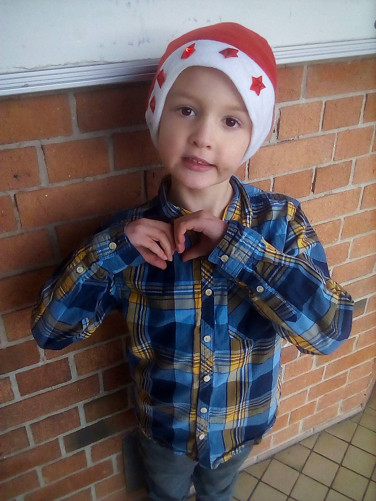 Corentin a rejoint le concours — aidez-le/la à gagner de superbes lots ! baseball_cap, brick, brickwork, cap, collar, cool, dress_shirt, electric_blue, headwear, neck, outerwear, pattern, person, plaid, sleeve, standing, street_fashion, t_shirt, tartan, toddler