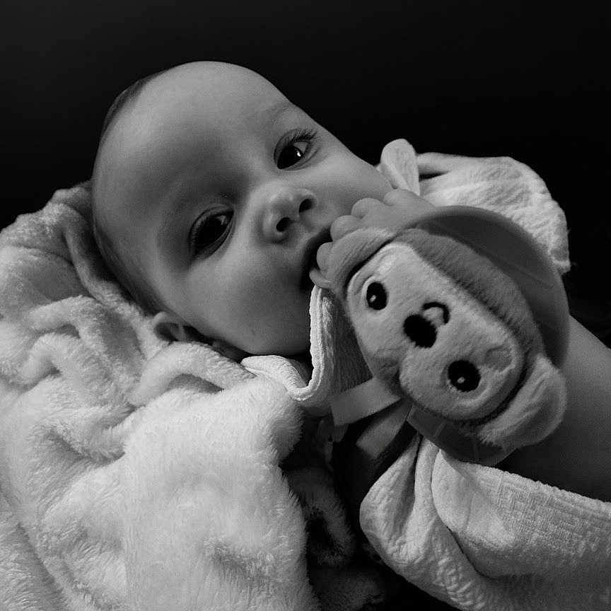 Emma joined the competition — help win amazing prizes! baby, blanket, black_and_white, child, cute, fluffy, face, infant, indoors, portrait, plush_toy, soft_texture, smiling_eyes, wrapped, young_child, hand, comfort, cozy, close_up, adorable