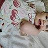 Emma joined the competition — help win amazing prizes! baby, infant, blanket, face, person, clothing, fruit_pattern, cherry, hand, skin, eyes, mouth, smile, carpet, soft_texture, lying_down, cute, young_child, indoors, portrait
