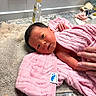 newborn, baby, pink_towel, bath_time, hand, countertop, beige_towel, bottle, sink, tile_wall, infant, wrapped, soft_texture, skin, small_hand, cute, indoors, cleaning, fresh, resting