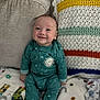 baby, infant, smiling, onesie, pajamas, blanket, couch, pillow, crochet_pillow, knitted_blanket, happy, portrait, cozy, seated, face, head, hands, patterned_blanket, living_room, cute